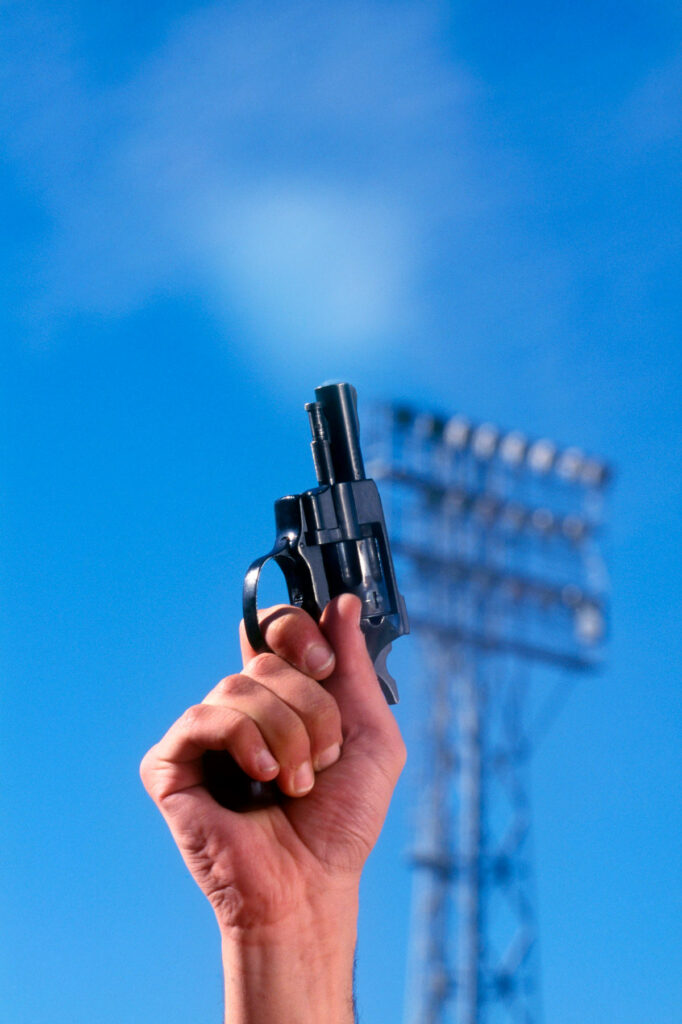A hand holding a starter pistol getting ready to start a race.