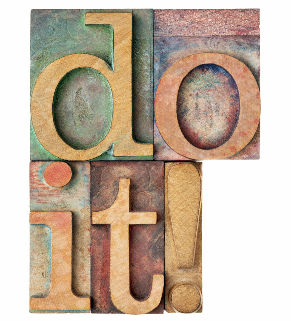 Motivation concept - isolated text in wood letterpress printing blocks stained by color inks that spell out Do It!