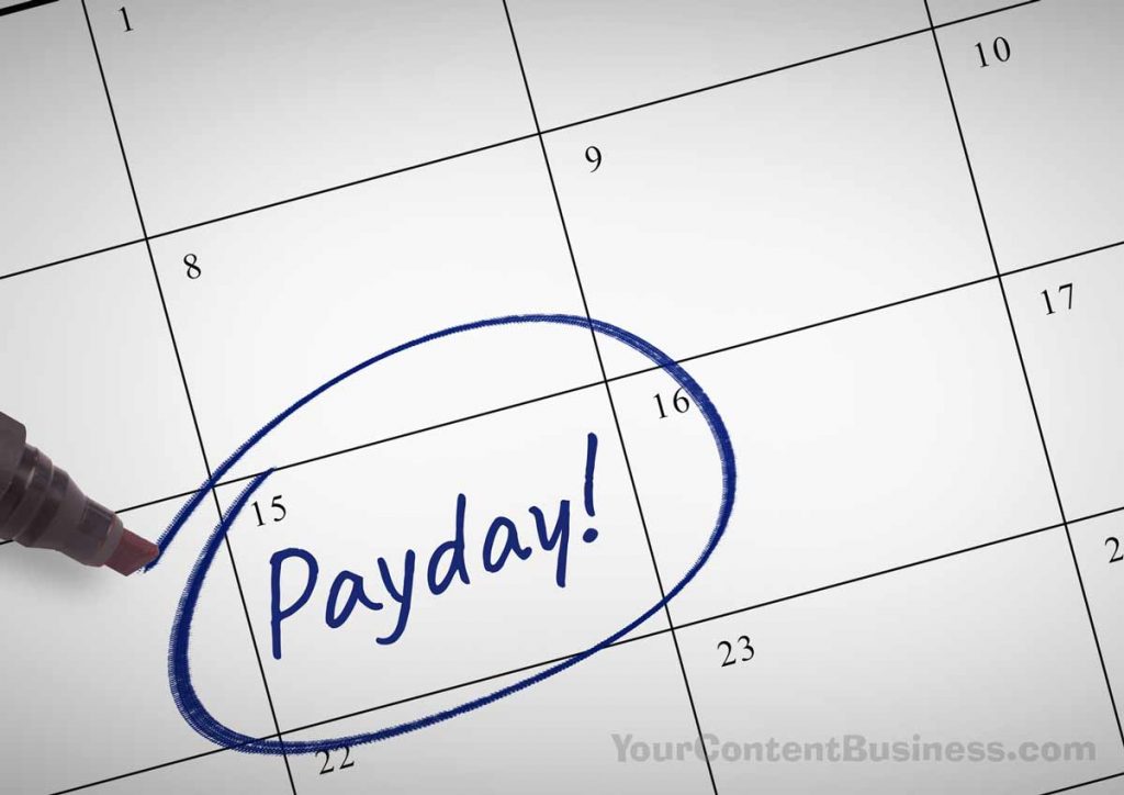 A desktop calendar with the word "Payday!" written on the square for the 15th of the month and circled in blue by a marker.